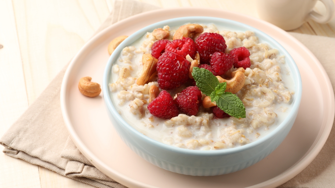 Činija ovsene kaše sa malinama i orašastim plodovima na stolu